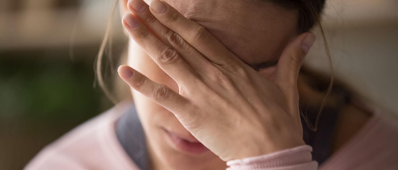 Frau hält gestresst die Hand vor die Stirn